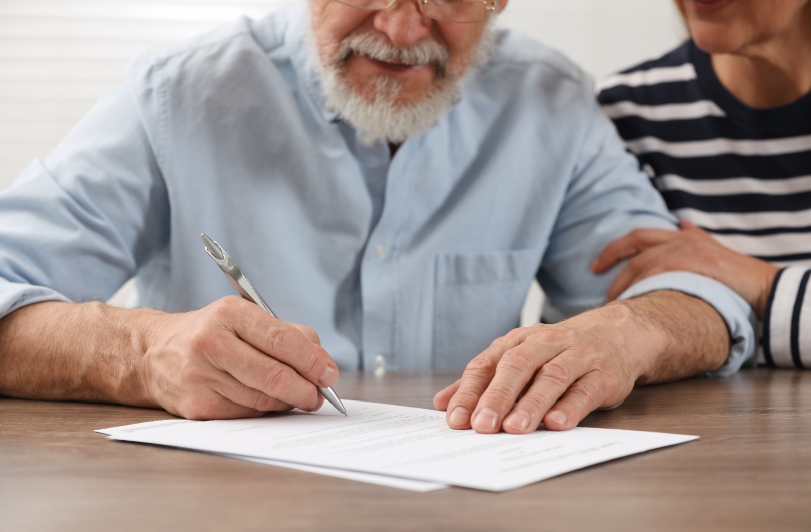 Close up of an older man and woman signing a Power of Attorney document.