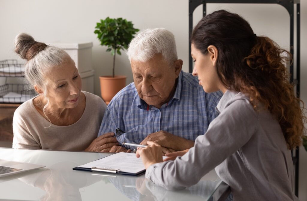 An older couple sitting at a table with a lawyer and looking at a document while the lawyer explains the document.