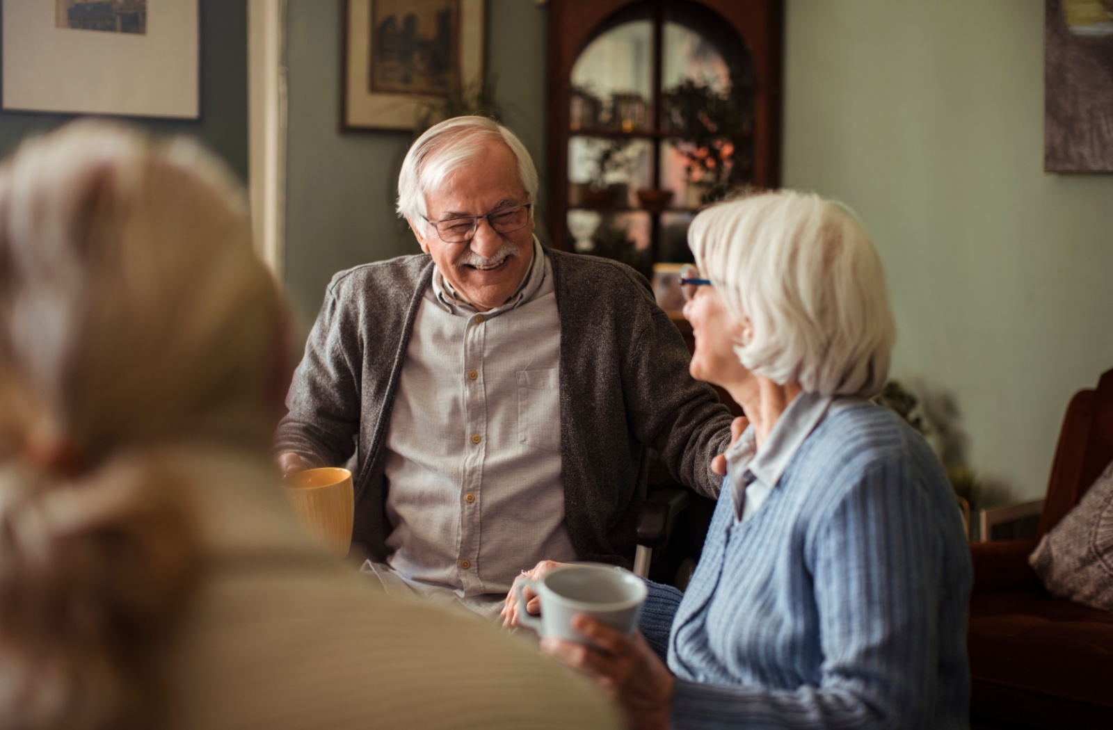 A group of seniors at an assisted living community enjoying a coffee together with friends.