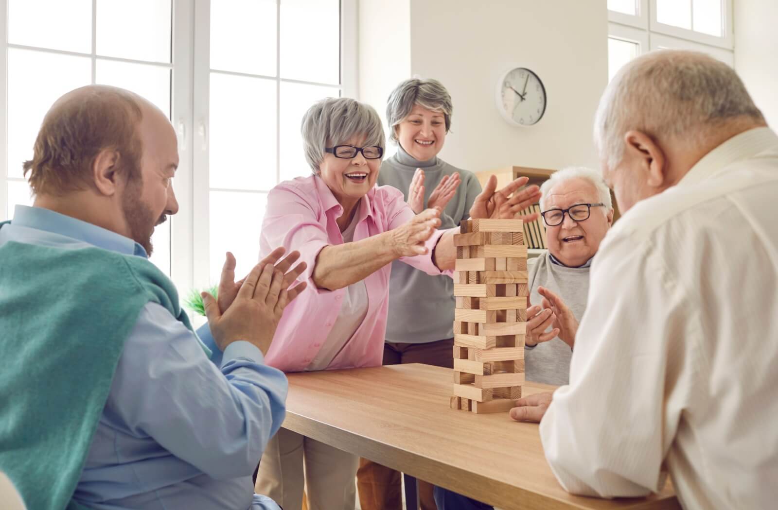 A group of seniors in assisted living happily play Jenga.