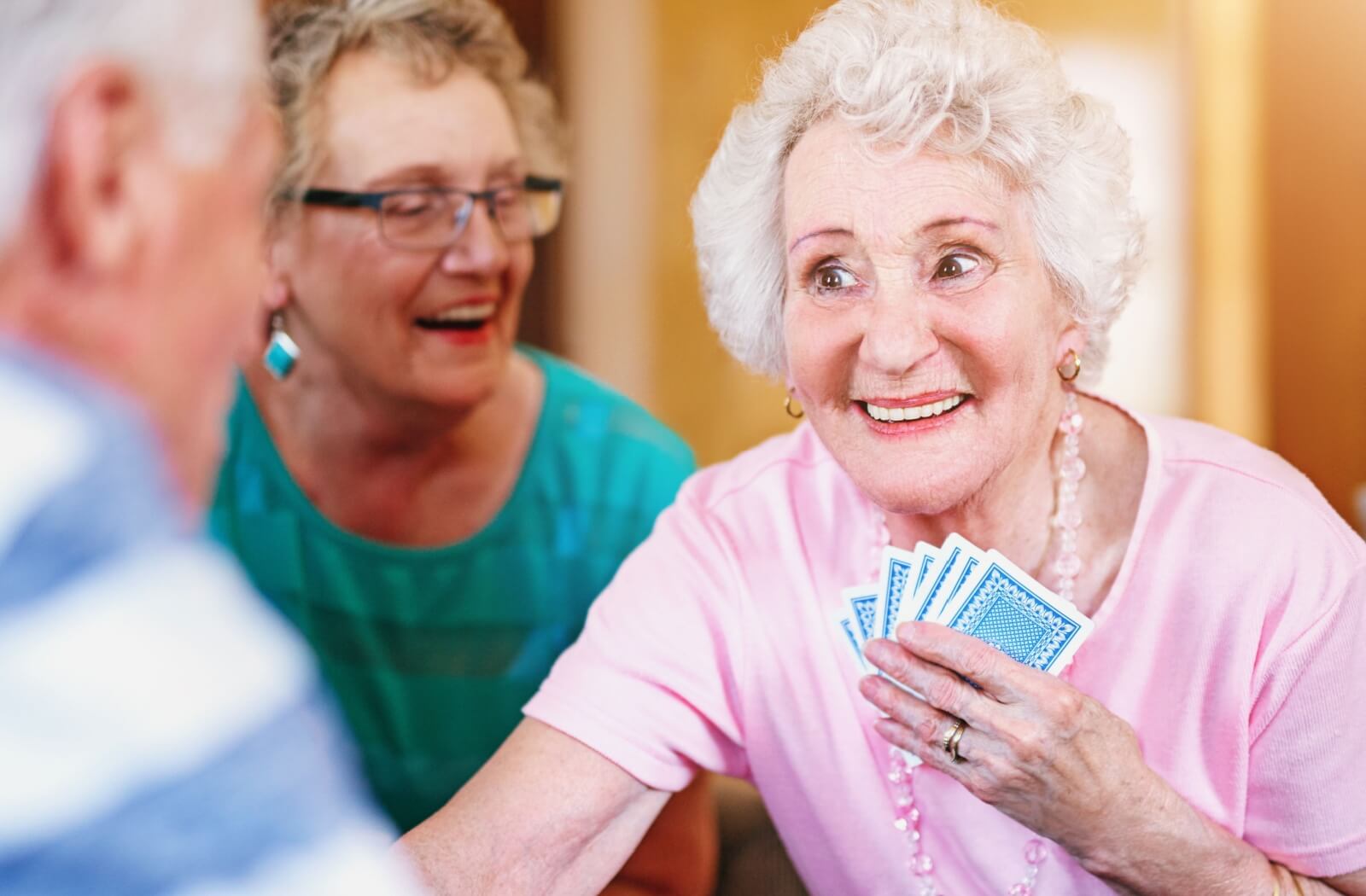 A lively older adult woman playing cards with her friends in assisted living.