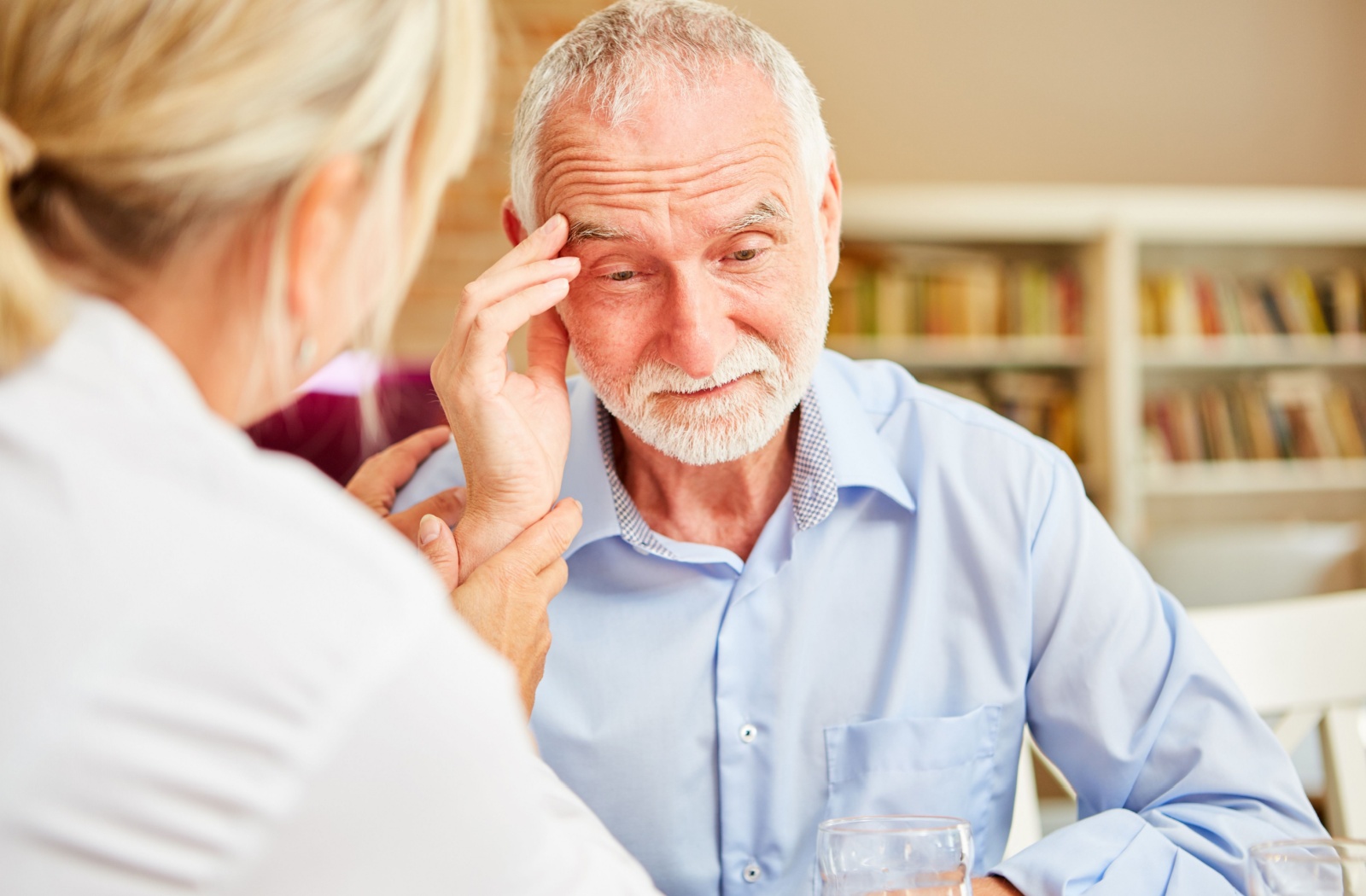 Elderly man with a thoughtful expression, receiving support from a caregiver