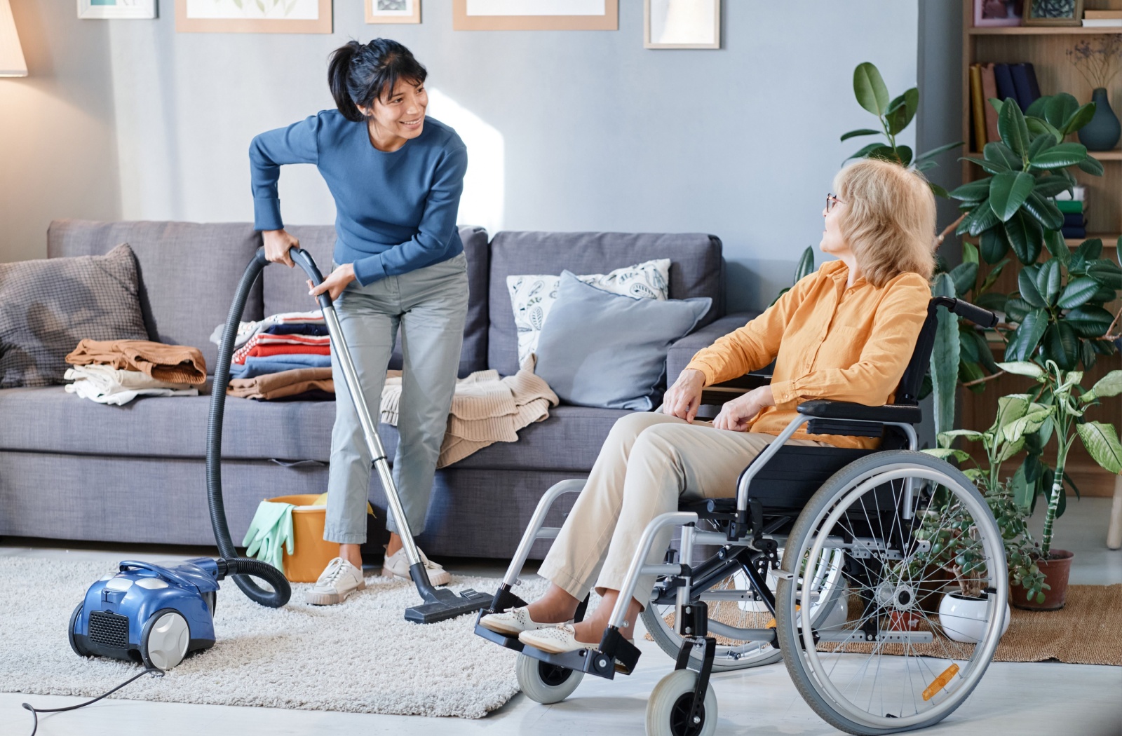 A senior using a wheelchair talks with the housekeeping staff before going to join social activities in assisted living