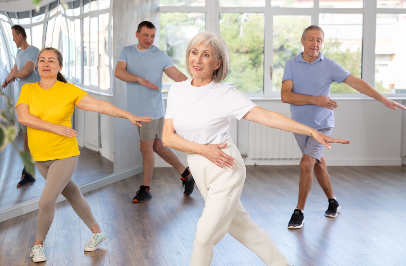 A close-up image of an older couple smiling while trying a new dance move in a group dance therapy session