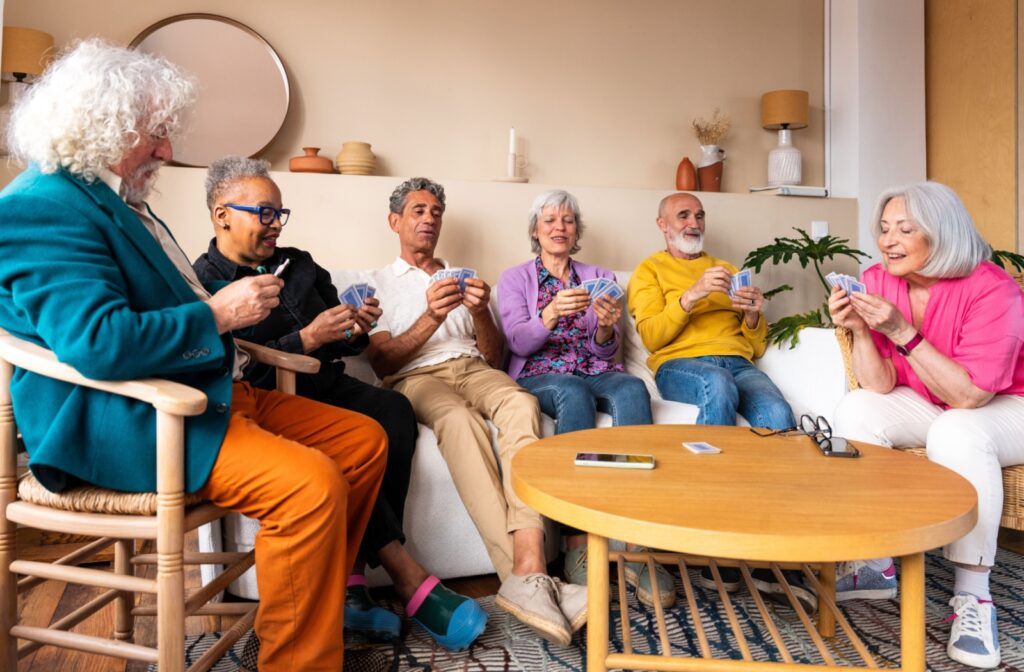 A group of seniors enjoy each other’s company over a game of cards in a communal area of their assisted living home