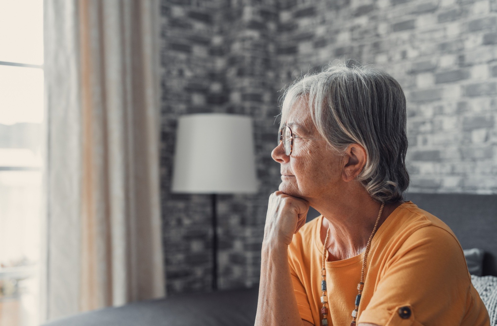 A senior in a yellow shirt placing their first under their chin in a sense of deep pondering
